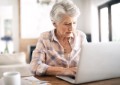 Shot of a serious senior woman using her laptop while sitting at the counter at home